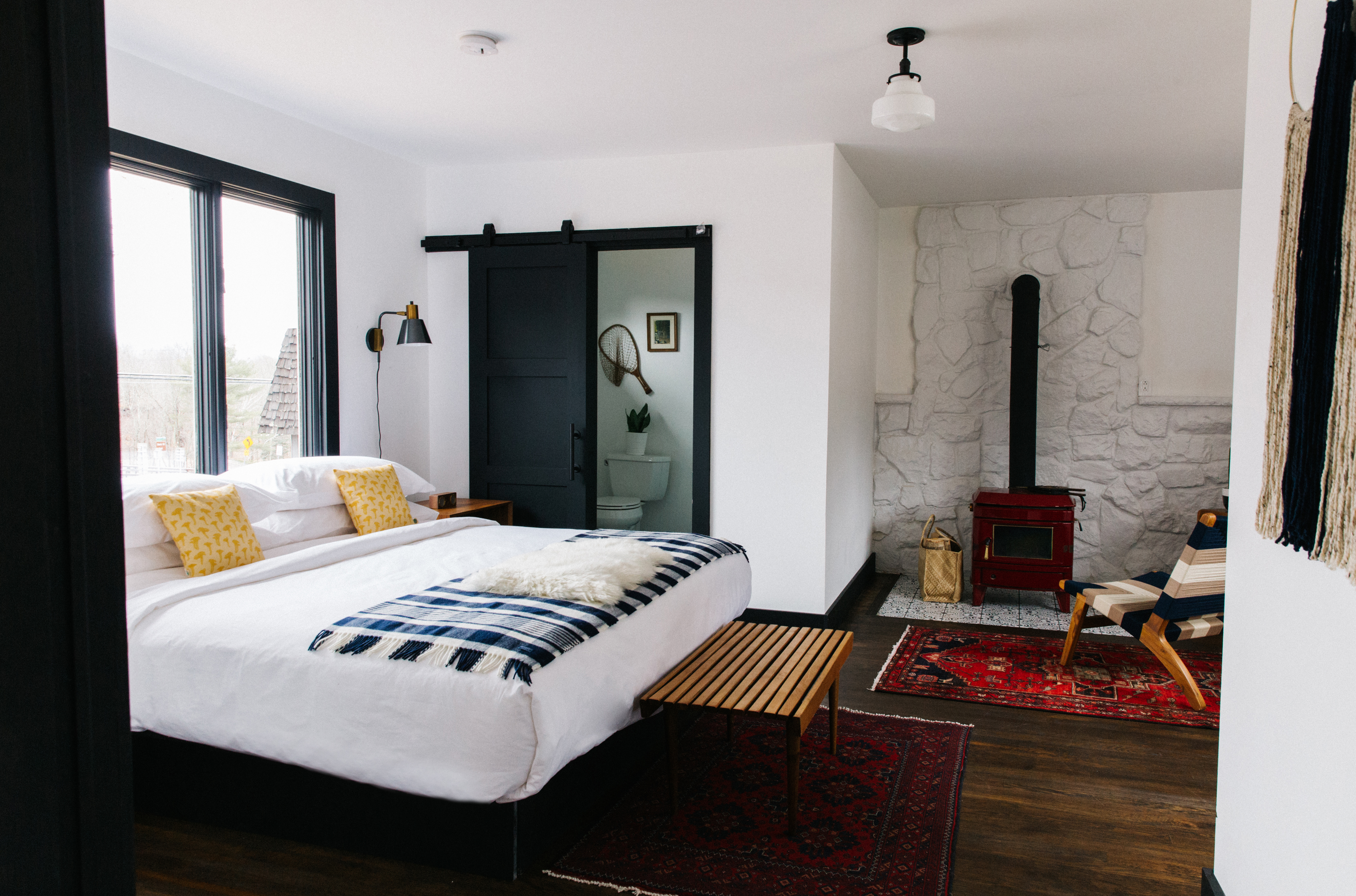 white and black room with queen bed and wood burning stove