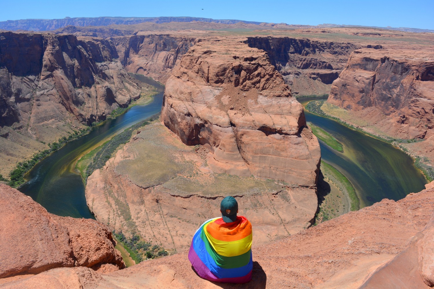 Mikah Meyer wearing a rainbow pride flag as he looks out over Horseshoe Bend