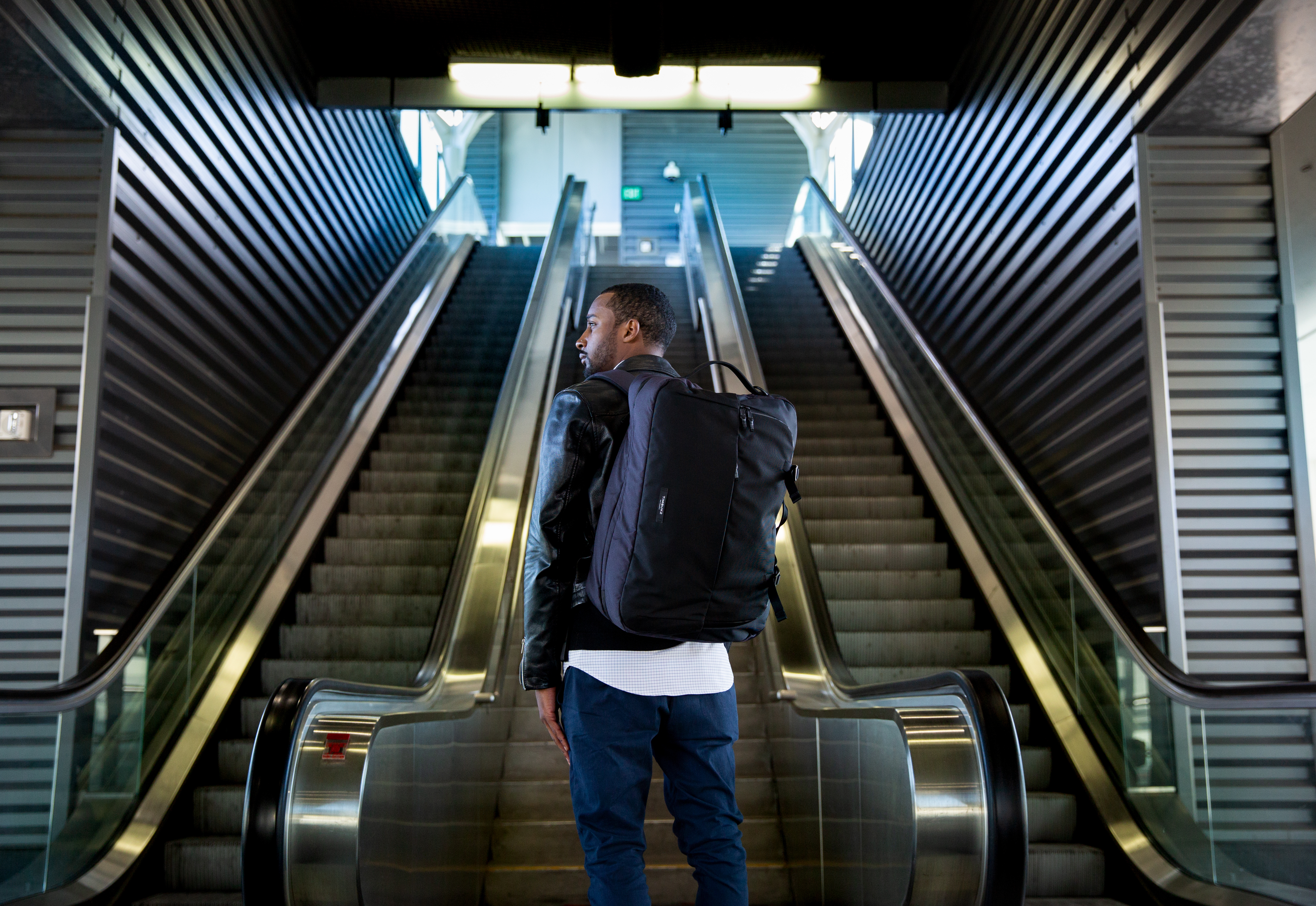 man with backpack at bottom of escalator