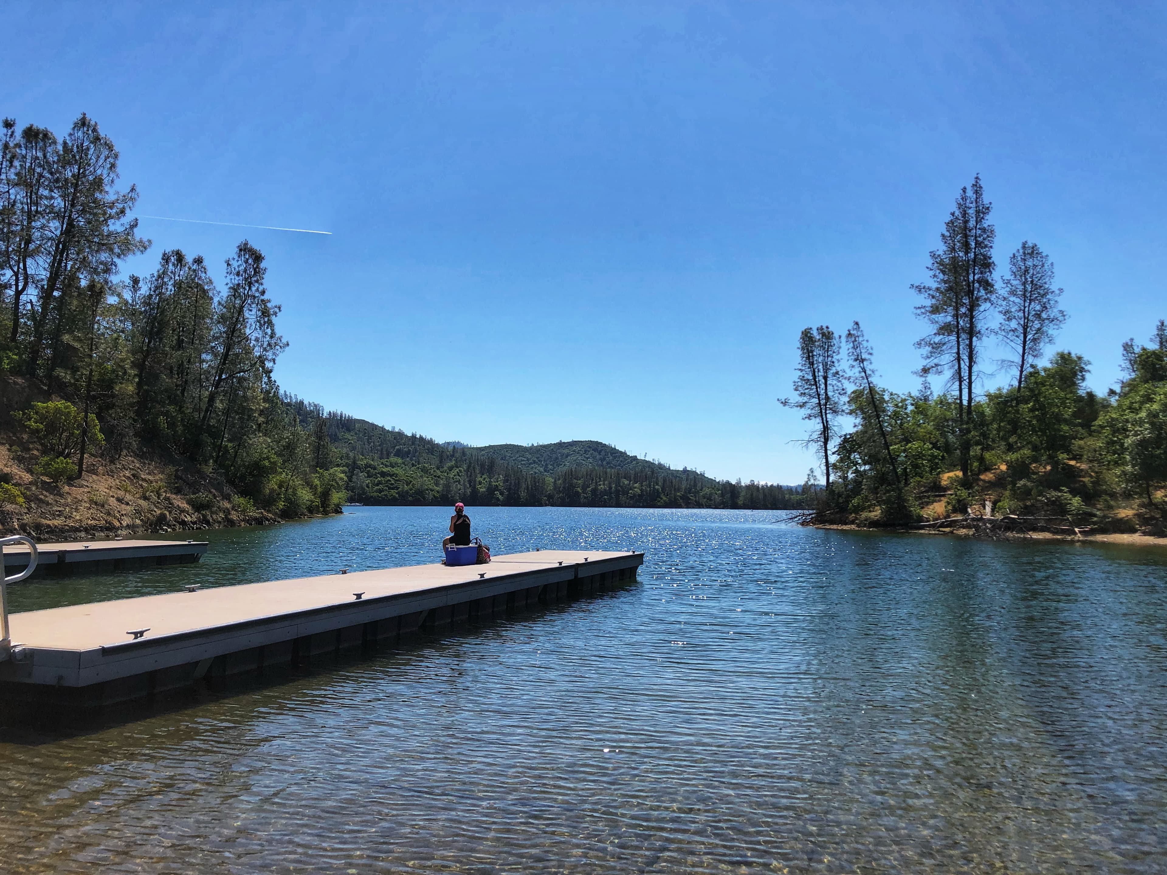 Blue sky dock on lake with person sitting
