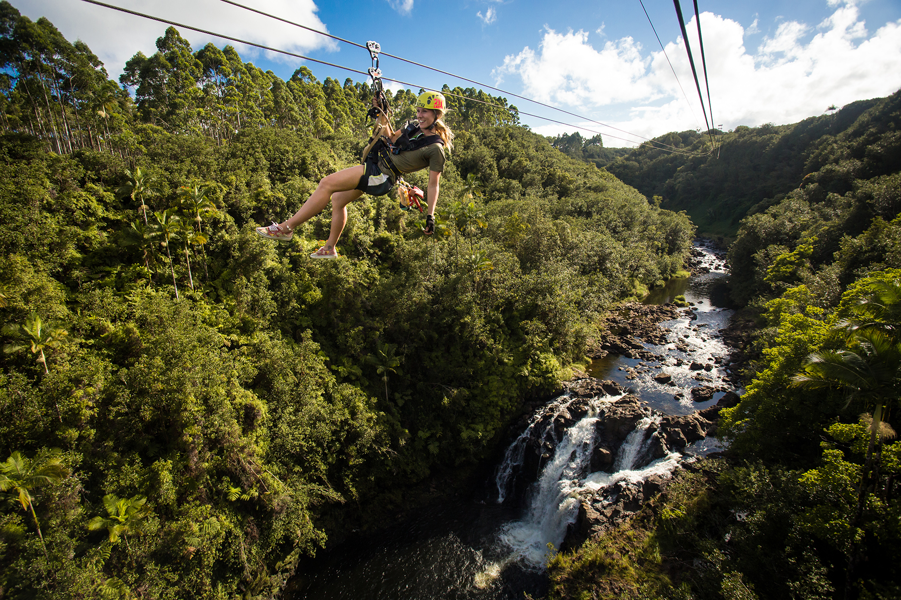Woman on zipline over river and waterfall