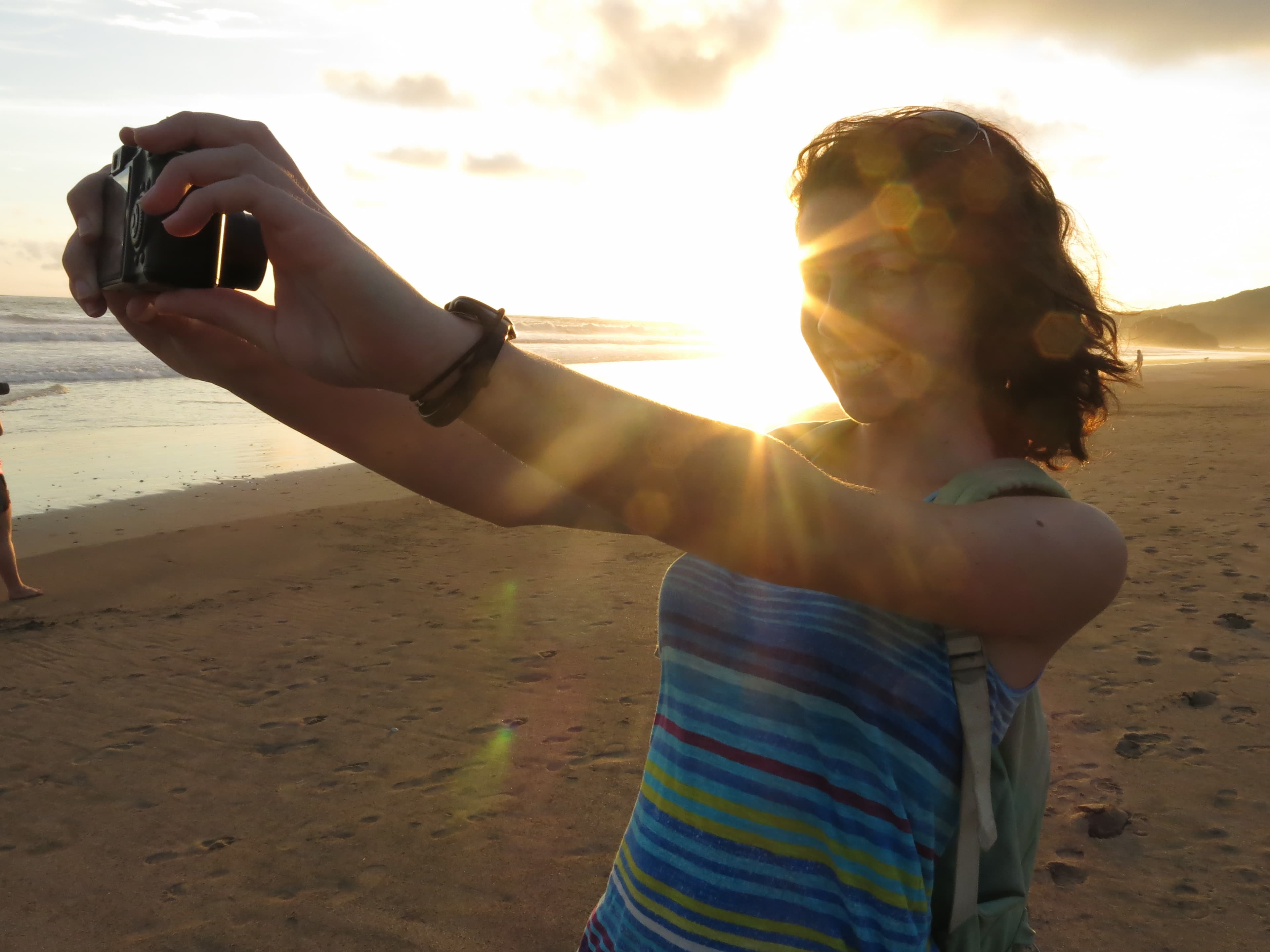 A solo traveler takes a photo of herself on the beach in Playa Grande, Costa Rica