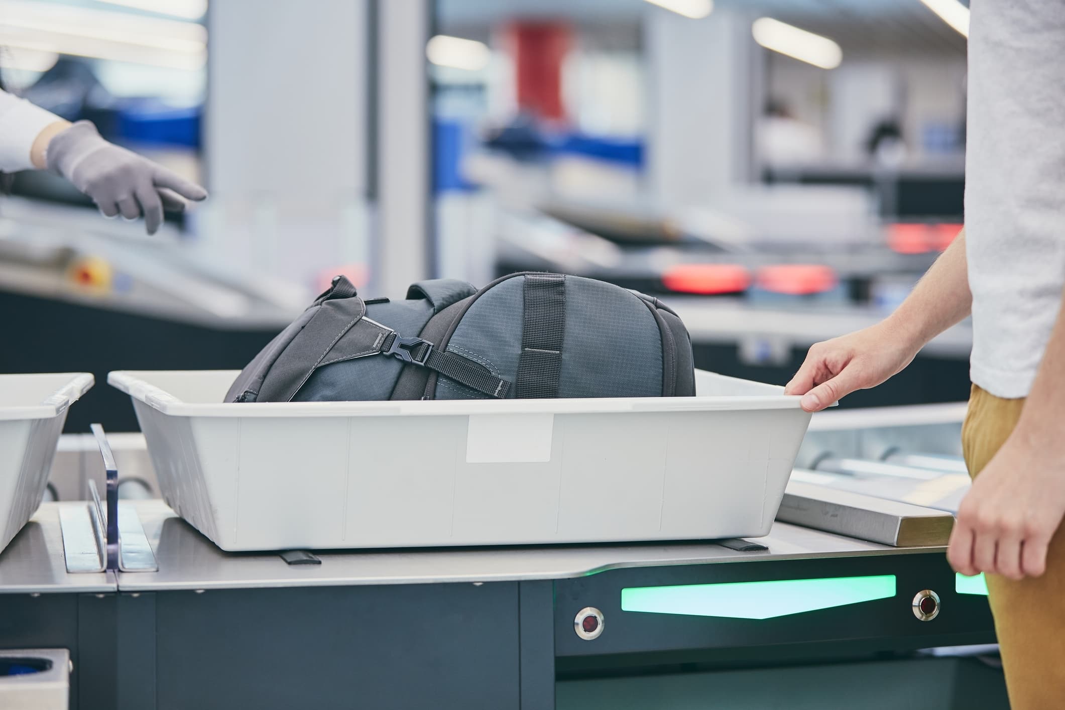 An airport security bin holds a passenger's bag awaiting x-ray