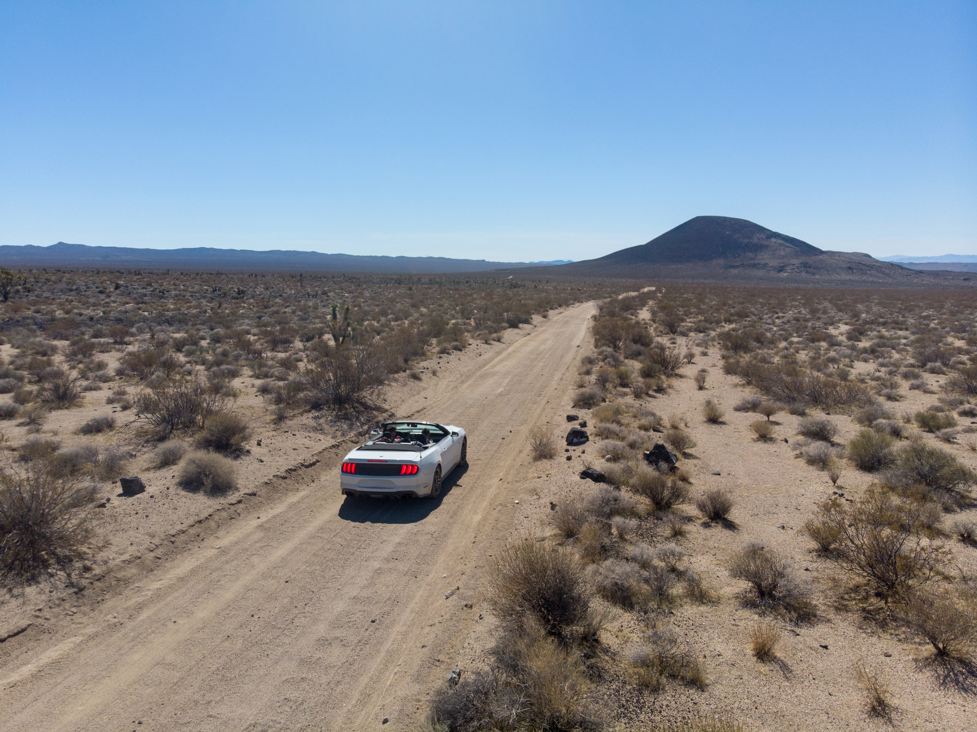An overhead view of a car on a desert highway.