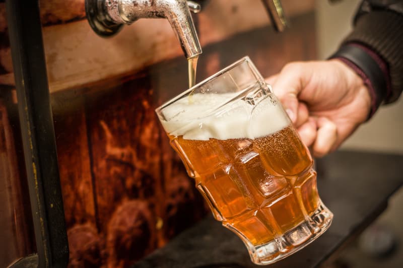 A pint glass being filled with craft beer.