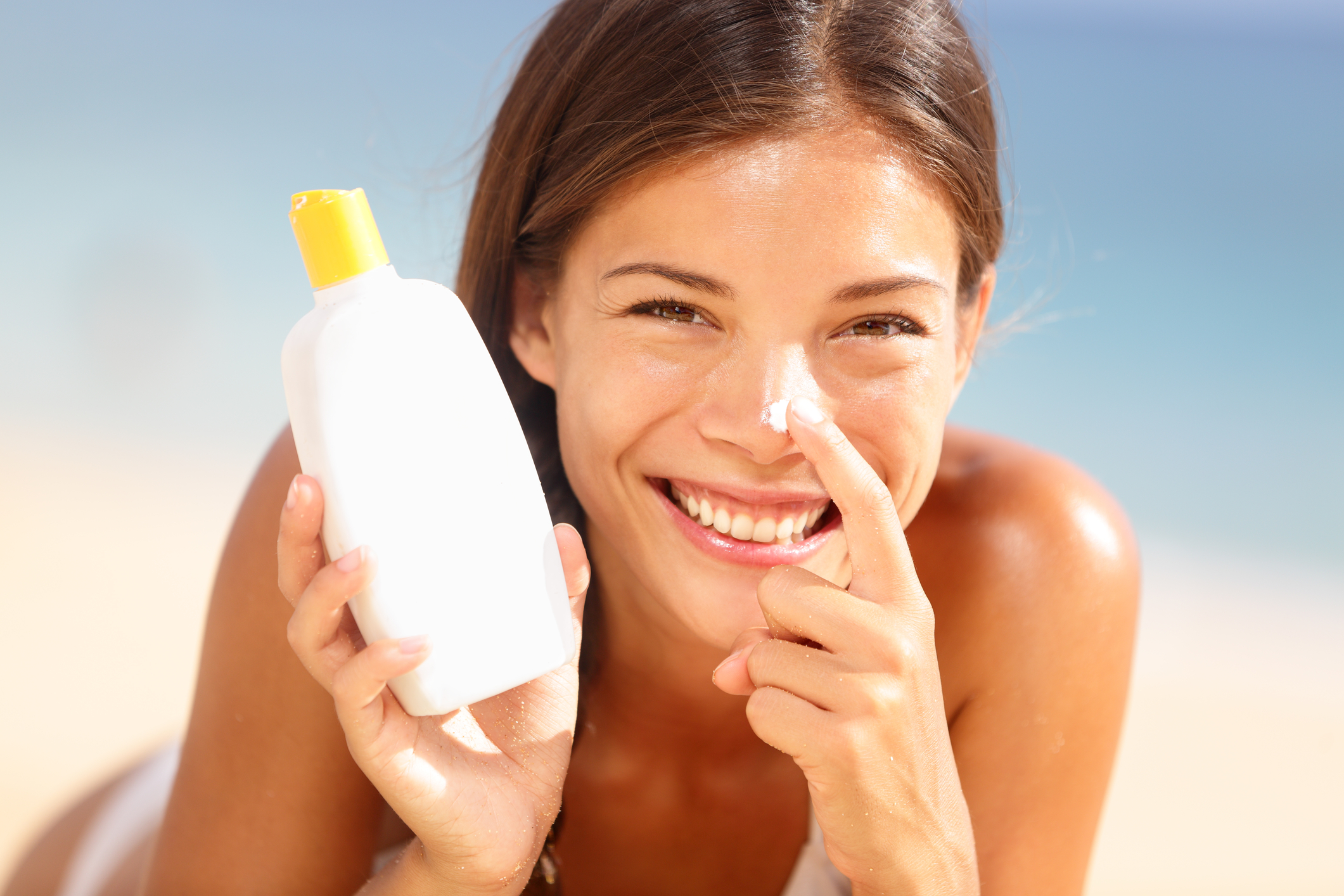 A smiling woman applying sunscreen