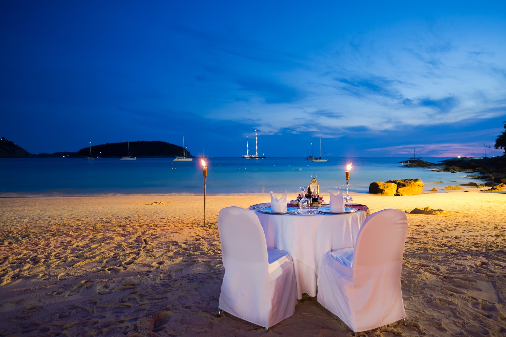 A romantic table with candles on a beach.