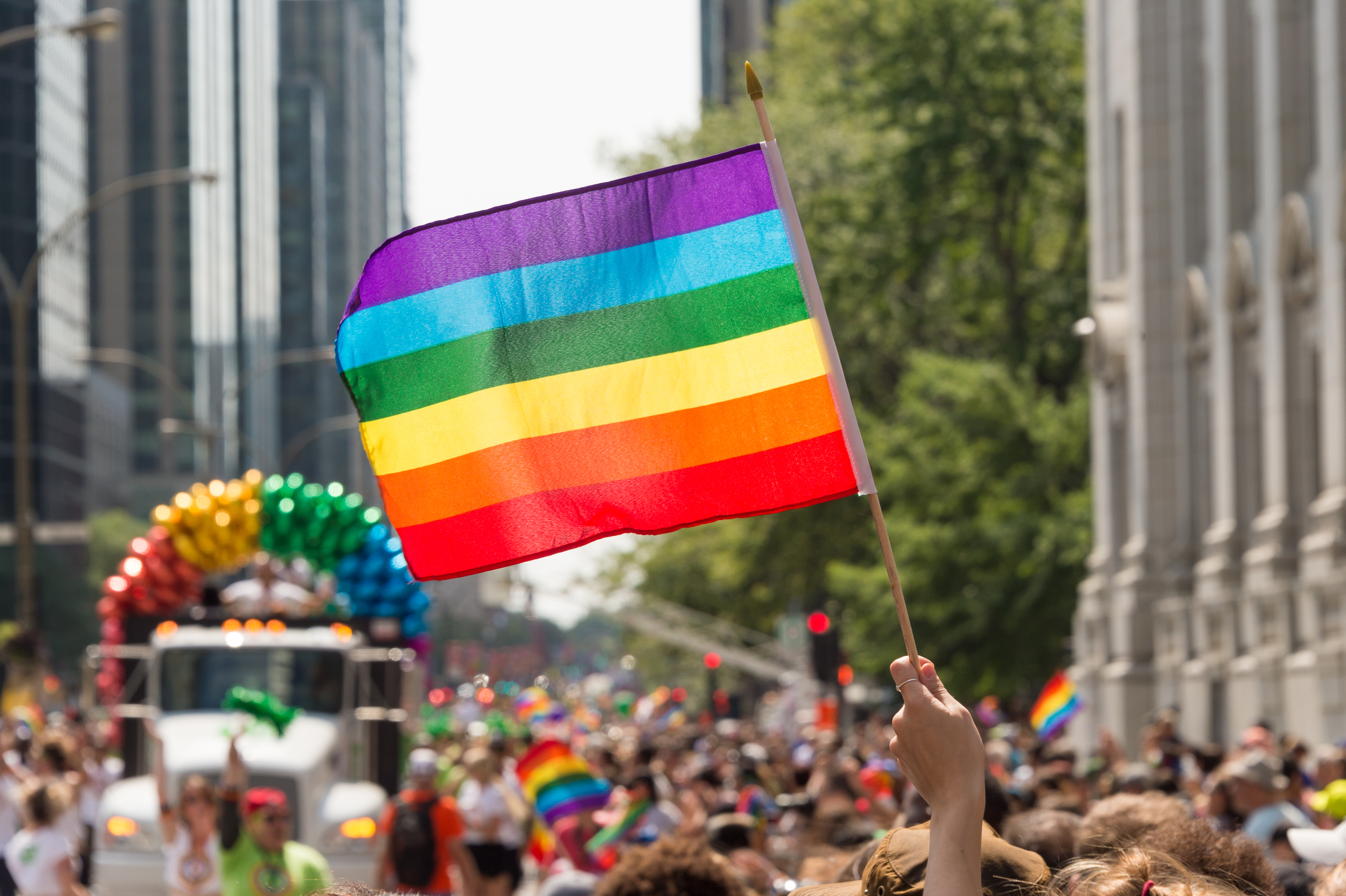 A view of Montreal's pride parade with a rainbow flag held high.