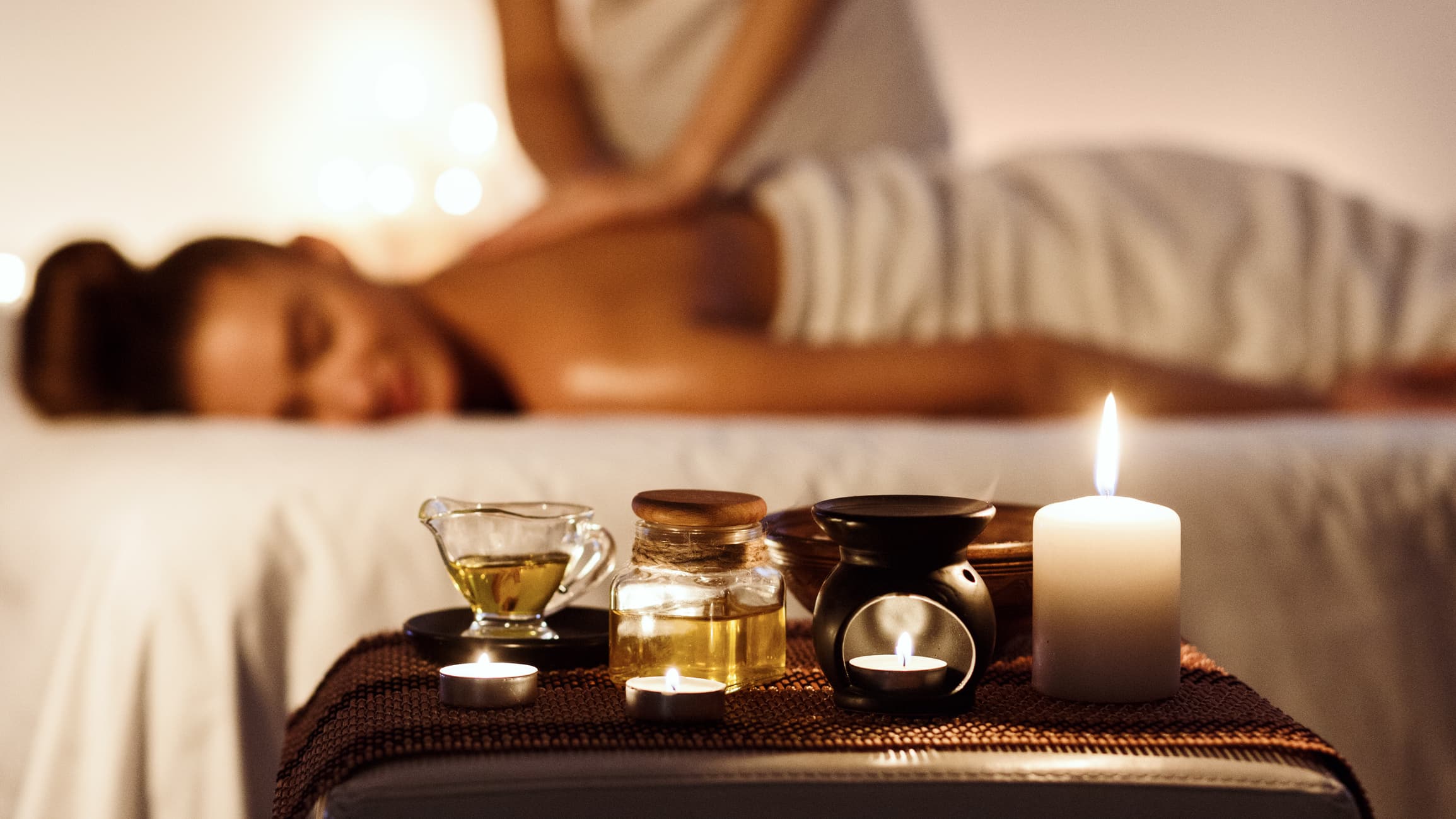 A woman's getting a massage with candles in the foreground