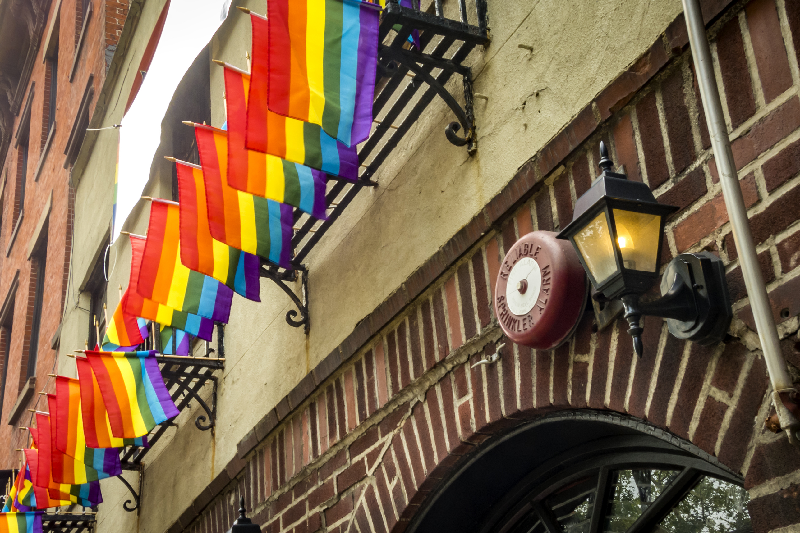 A street view of NYC's Stonewall Inn with rainbow flags.