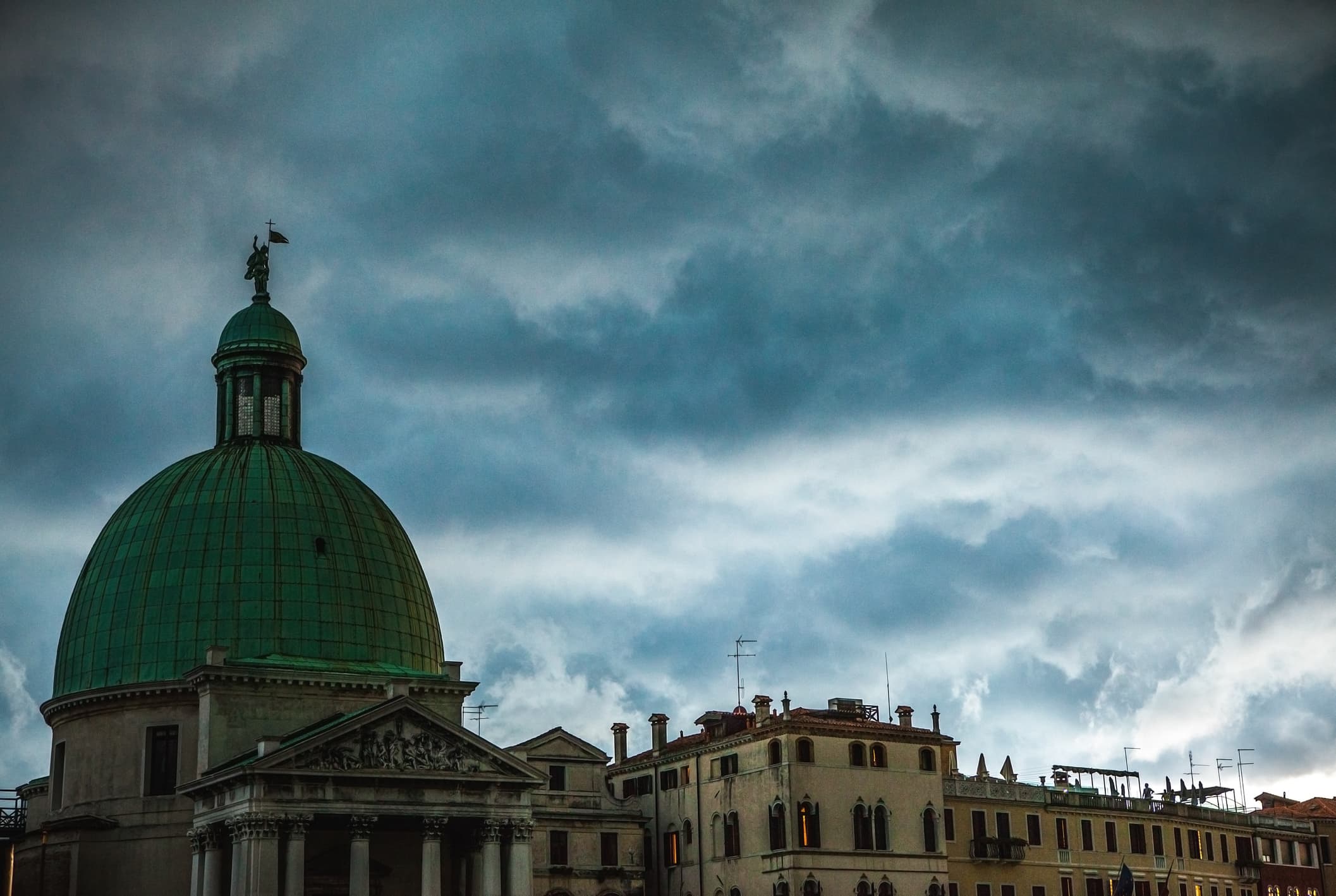 A dome in Venice with storm clouds gathering behind it.