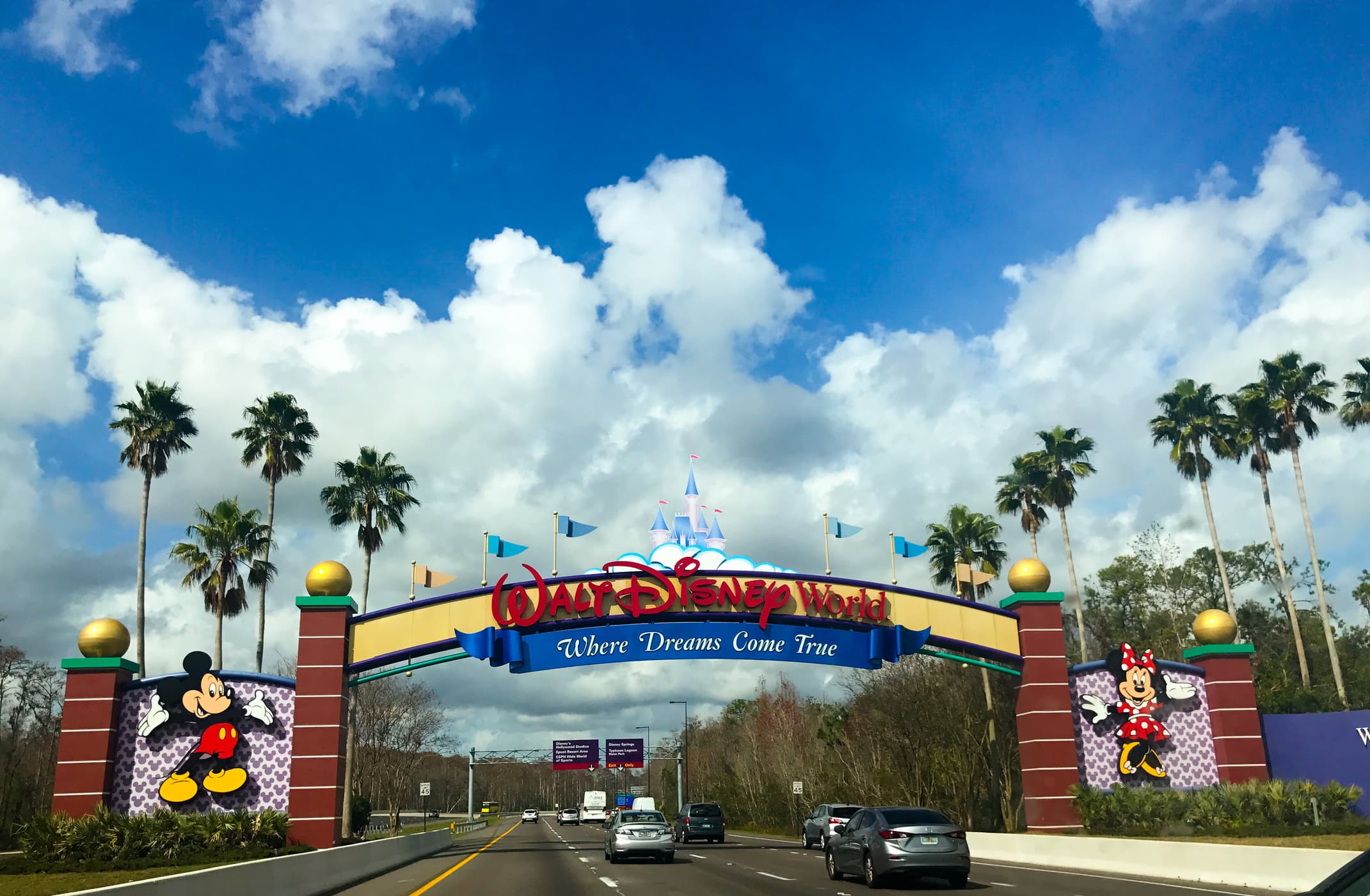 A view of cars entering Walt Disney World, Orlando, with a sign and image of Mickey Mouse